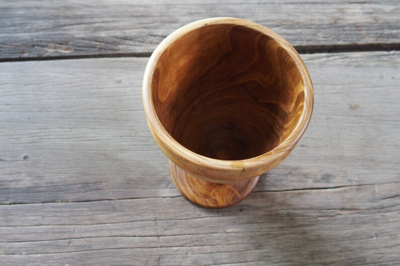 May include: A wooden bowl with a natural wood finish. The bowl is empty and has a rounded bottom.