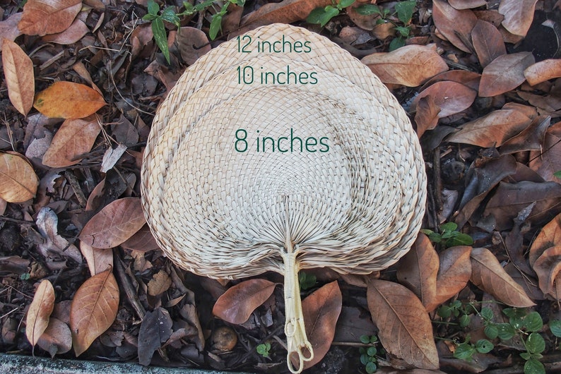 May include: A large, white, woven fan with a handle. The fan is 12 inches wide, 10 inches tall, and 8 inches in diameter.