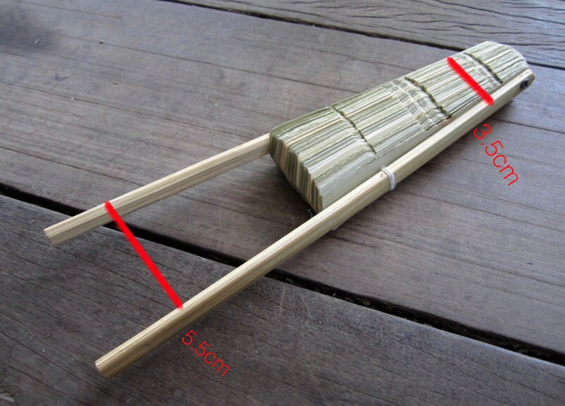 K&ouml;nnte beinhalten: Ein geschlossener, faltbarer F&auml;cher aus Holz mit nat&uuml;rlicher Oberfl&auml;che. Der F&auml;cher ist 9,5 cm lang und 5 cm breit.
