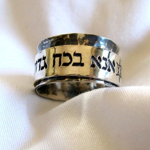 Puede incluir: Un anillo de plata con acabado martillado y texto en hebreo que dice "אהבה גדולה" que se traduce como "Gran Amor".
