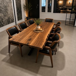 Könnte beinhalten: Ein rechteckiger Esstisch mit einer natürlichen Baumkanten-Holzplatte und einem schwarzen Metallgestell, umgeben von acht Holzarmlehnstühlen mit schwarzen Polstersitzen und Rückenlehnen, mit einer kleinen Vase und Kerze auf dem Tisch.