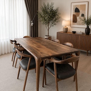 May include: A rectangular dining table crafted from dark brown wood with a smooth grain, accompanied by six matching chairs featuring curved wooden backrests and black upholstered seats, arranged around the table on a light-colored area rug.