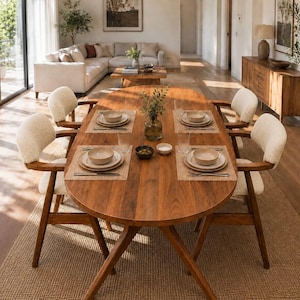 May include: An oval wooden dining table with four chairs featuring cream-coloured upholstered seats and backrests. The table is set with four place settings, each including a plate, a bowl, and silverware on a woven placemat, with a glass vase in the centre.