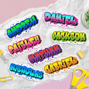 May include: A collection of colorful name stickers in a graffiti style. Names include Andrew, Daniel, Paisley, Jackson, Nathan, Nicholas, and Gabriel. Each sticker features a unique color scheme with a white border and paint splatter accents.