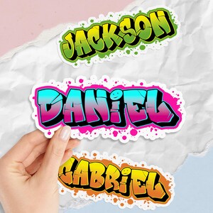 May include: Three colorful graffiti-style name stickers: "Jackson" in green and yellow, "Daniel" in blue and pink, and "Gabriel" in orange and yellow. Each sticker has a black outline and a splatter effect.
