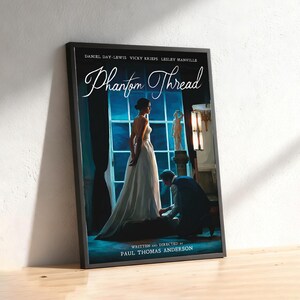 May include: Framed poster for the film "Phantom Thread", starring Daniel Day-Lewis, Vicky Krieps, and Lesley Manville. The artwork shows a woman in a white dress, a man kneeling, and the film's title.