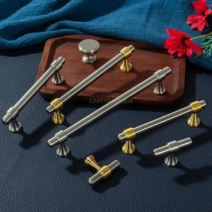 K&ouml;nnte beinhalten: Eine wei&szlig;e Keramik-Tasse mit schwarzem Henkel und dem Text "But First, Coffee" in fetter, schwarzer Schrift. Die Tasse steht vor einem neutralen Hintergrund, der ihr schlichtes Design hervorhebt.