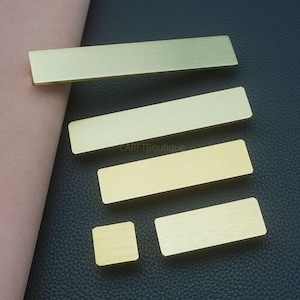 Op de afbeelding: Een verzameling rechthoekige en vierkante messing hardware. De stukken hebben een geborstelde afwerking en variëren in grootte. De afbeelding bevat de tekst "CARFTBoutique". De hardware wordt op een donkere ondergrond weergegeven.