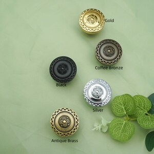 May include: Decorative cabinet knobs in gold, coffee bronze, black, silver, and antique brass. Each knob features a circular design with a central floral pattern and geometric border. The colors are labeled: Gold, Coffee Bronze, Black, Silver, and Antique Brass.