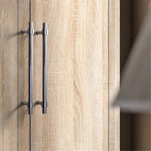 Peut inclure: Gros plan sur une porte d'armoire en bois clair avec deux poign&eacute;es de barre verticales en nickel bross&eacute;. Les poign&eacute;es sont mont&eacute;es avec de petits supports carr&eacute;s. La porte de l'armoire a une finition en bois naturel.