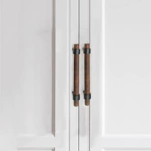 以下が含まれることがあります： 白いキャビネットドアのクローズアップ。2つの垂直な円筒形のキャビネットプルがあります。プルは濃い茶色の木材と黒い金属のアクセントで作られています。キャビネットドアは2つのパネルに分かれています。