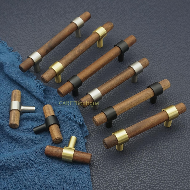 以下が含まれることがあります： シルバー、ゴールド、ブラックの金属アクセントが付いた木製キャビネットプルコレクション。 プルは円筒形の木製ハンドルを備え、家具用に設計されています。 ハードウェアは濃い青色の表面に表示されます。