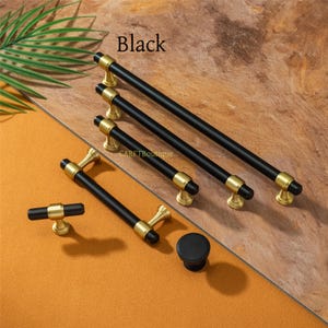 Pode incluir: Uma cole&ccedil;&atilde;o de ferragens para arm&aacute;rios pretas e douradas, incluindo puxadores e um bot&atilde;o. Os puxadores t&ecirc;m um acabamento preto fosco elegante com detalhes dourados. A palavra "Black" est&aacute; impressa no canto superior esquerdo.