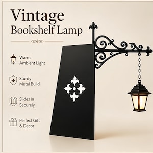May include: A black metal bookshelf lamp featuring a decorative scrollwork bracket and a hanging lantern with warm light. The lamp includes a flat vertical panel with a white fleur-de-lis emblem. Text on the image reads Vintage Bookshelf Lamp.