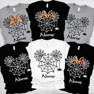 May include: A collection of six short-sleeved t-shirts in black, white, and grey. Each shirt features a graphic of three spider webs arranged in a mouse-ear shape, with the word Name printed below and some designs including an orange polka-dot bow.
