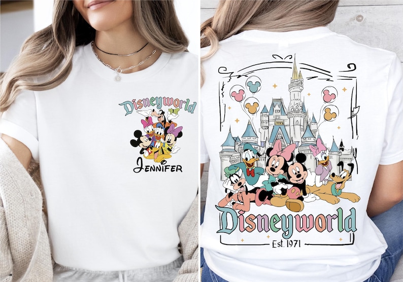 Op de afbeelding: Wit T-shirt met Disney-personages, waaronder Mickey en Minnie Mouse, Donald Duck en Goofy. De voorkant heeft een groep personages en de naam "Jennifer". De achterkant toont een kasteel en de tekst "Disneyworld Est. 1971".