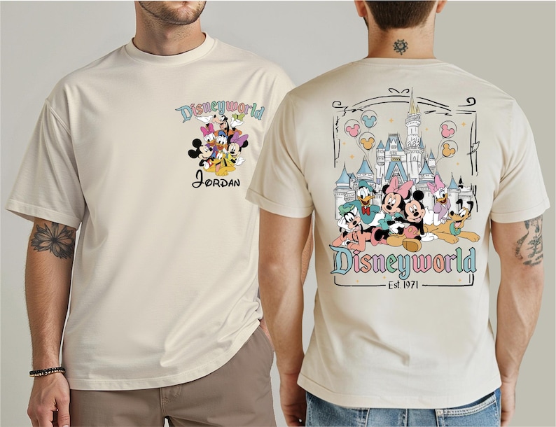 Op de afbeelding: Cr&egrave;mekleurig T-shirt met een Disney World-ontwerp. De voorkant toont Disney-personages en de naam "Jordan". De achterkant toont het Disney World-kasteel en meer personages, met "Disneyworld Est. 1971".