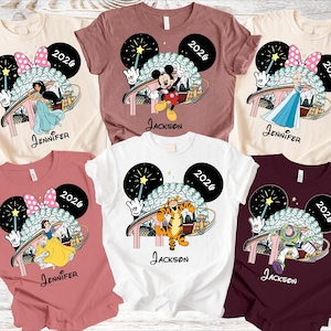 May include: Assorted-color t-shirts featuring Disney characters like Mickey Mouse, Elsa, and Tigger. Each shirt has a unique design with the character's image, the year 2026, and a name. The shirts are short-sleeved.