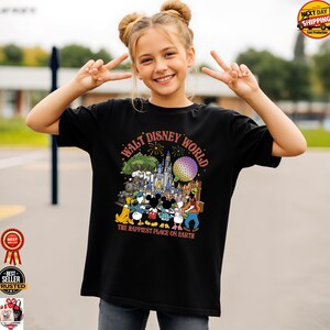 May include: Black t-shirt featuring a colorful graphic of Disney characters and the text "WALT DISNEY WORLD THE HAPPIEST PLACE ON EARTH." The design includes a castle, Spaceship Earth, and fireworks. The shirt is worn by a person making a peace sign.