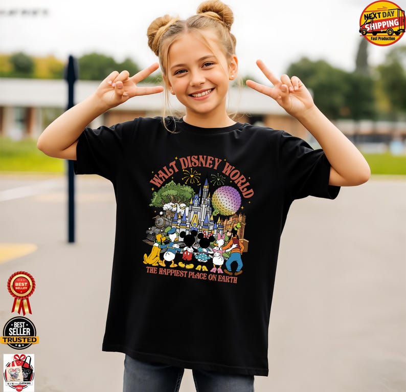 May include: Black t-shirt featuring a colorful graphic of Disney characters and the text "WALT DISNEY WORLD THE HAPPIEST PLACE ON EARTH." The design includes a castle, Spaceship Earth, and fireworks. The shirt is worn by a person making a peace sign.