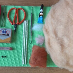 Puede incluir: Un conjunto de materiales de artesan&iacute;a para hacer un animal de fieltro. Los materiales incluyen un paquete de arcilla polim&eacute;rica Fimo Effect, un par de alicates, un par de tijeras, cuatro limpiapipas blancos, una herramienta de metal, un tubo de pegamento, una peque&ntilde;a cantidad de lana blanca y rosa, una peque&ntilde;a cantidad de lana marr&oacute;n y dos cuentas negras.