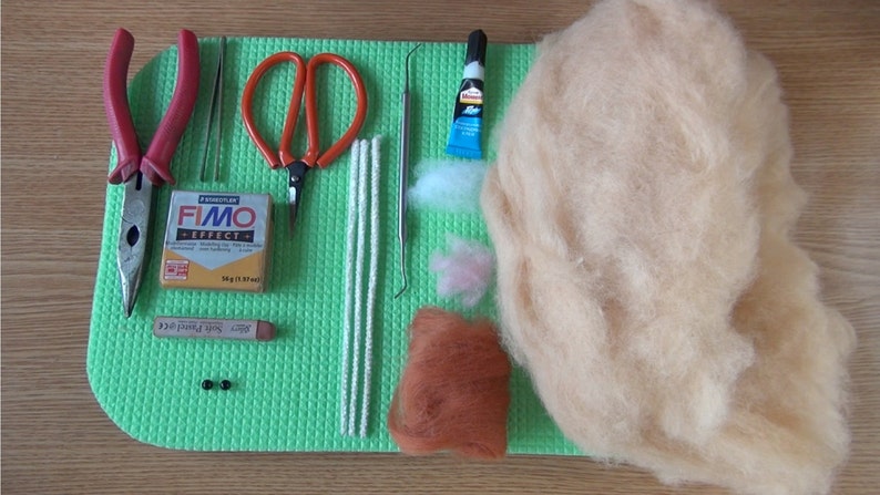 Puede incluir: Un conjunto de materiales de artesan&iacute;a para hacer un animal de fieltro. Los materiales incluyen un paquete de arcilla polim&eacute;rica Fimo Effect, un par de alicates, un par de tijeras, cuatro limpiapipas blancos, una herramienta de metal, un tubo de pegamento, una peque&ntilde;a cantidad de lana blanca y rosa, una peque&ntilde;a cantidad de lana marr&oacute;n y dos cuentas negras.