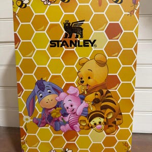 May include: A yellow box with a honeycomb pattern and illustrations of Winnie the Pooh characters. The box features the Stanley logo and images of bees, honey, and flowers. Characters include Winnie the Pooh, Piglet, Eeyore, and Tigger.