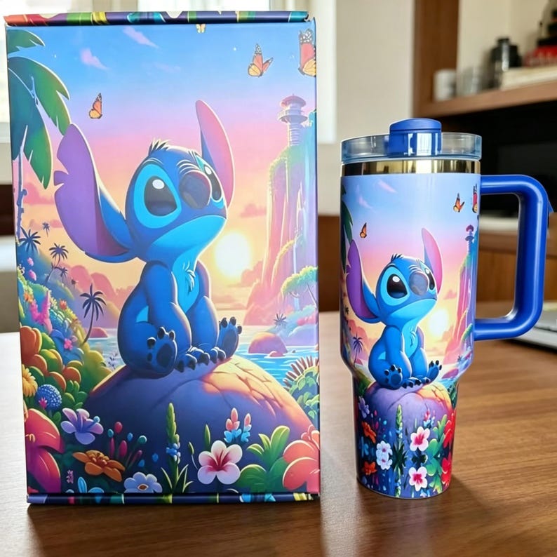 May include: A rectangular cardboard box and a matching stainless steel tumbler with a handle, both featuring a vibrant illustration of the blue character Stitch sitting on a rock amidst a tropical landscape with flowers, butterflies, and a sunset.