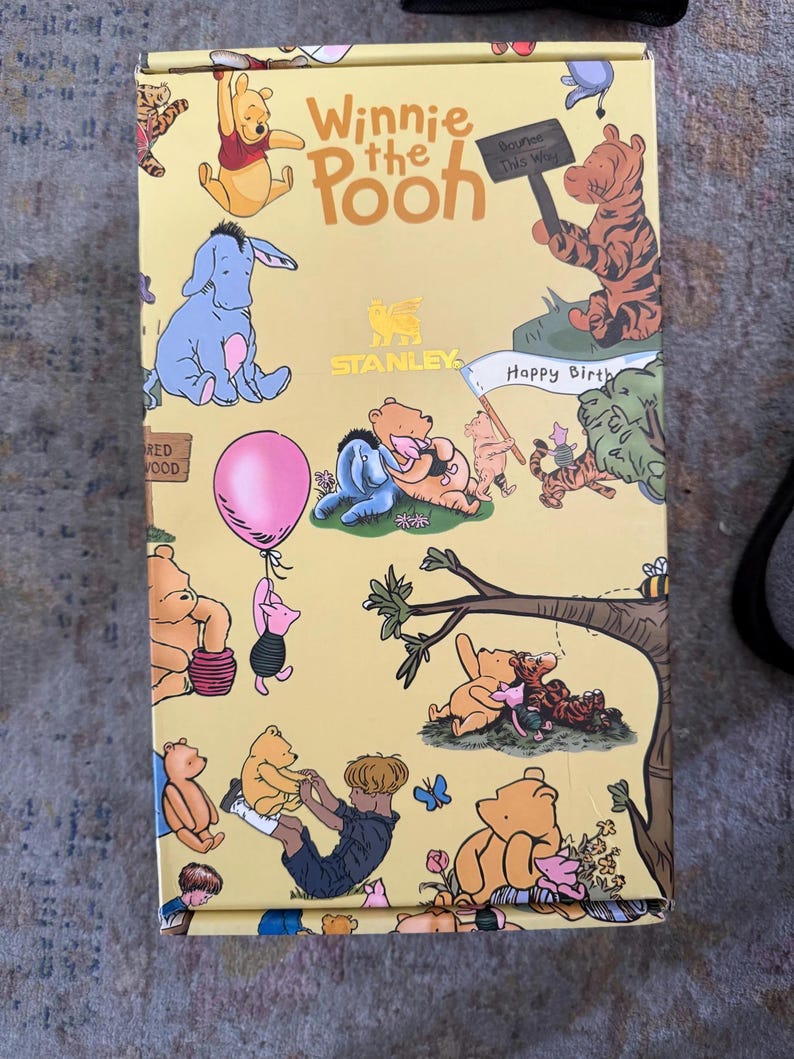 May include: A yellow box featuring illustrations of Winnie the Pooh characters. The box has the words "Winnie the Pooh" in large letters. Various characters are depicted, including Pooh, Eeyore, Piglet, and Tigger. The box also has the Stanley logo.