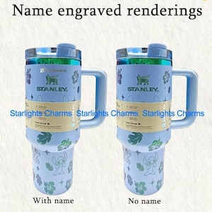 K&ouml;nnte beinhalten: Zwei hellblaue Stanley-Becher mit Griffen, einer mit der Aufschrift "Mit Name" und der andere "Ohne Name". Beide haben Blumen- und Charakterdesigns, das Stanley-Logo und den Text "Name engraved renderings."