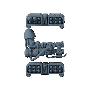 Op de afbeelding: Een grijze plastic miniatuuronderdelenset met een centraal armstuk met schouderstuk en aangehechte slangen, geflankeerd door twee identieke rechthoekige raketwerper-pods, elk met twaalf cirkelvormige raketbuizen gerangschikt in twee rijen.