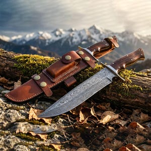 May include: A Damascus steel hunting knife with a wooden handle and a brown leather sheath. The knife is resting on a log with a backdrop of mountains and a cloudy sky. The sheath has brass-colored rivets.