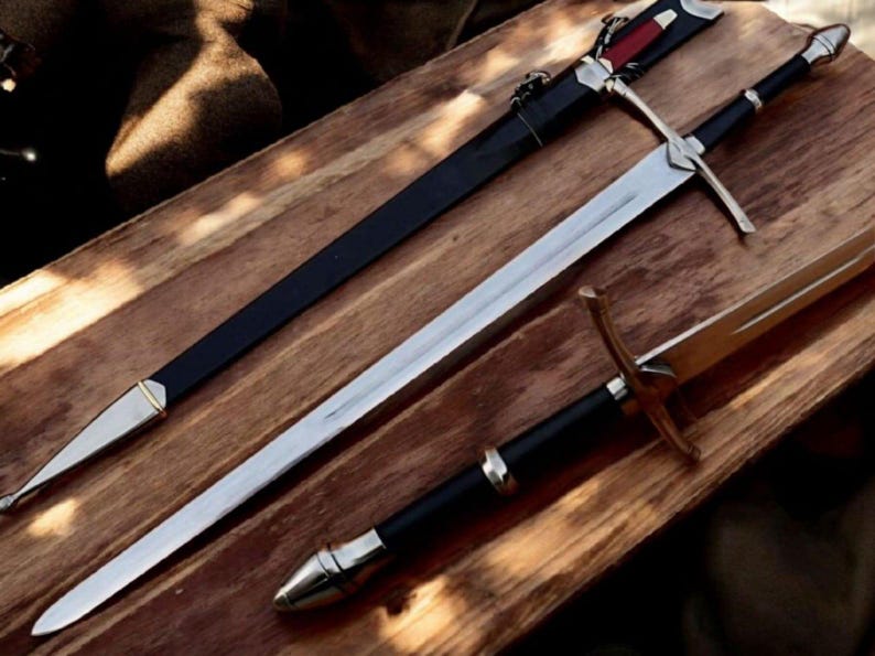 May include: Three swords with sheaths on a wooden surface. The swords have silver blades and black handles. One sword has a black sheath with silver accents, and another has a gold hilt.