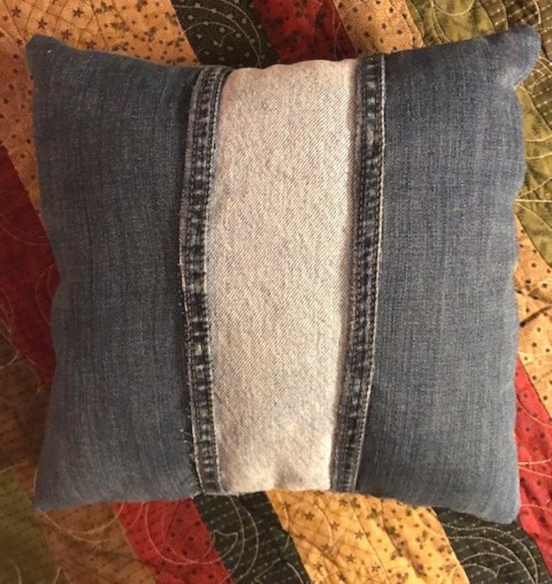 Pu&ograve; includere: Un cuscino in denim blu con un pannello centrale in denim bianco. Il cuscino &egrave; realizzato in denim riciclato e presenta un design unico a patchwork.