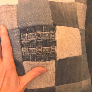 Pu&ograve; includere: Un cuscino quadrato realizzato in tessuto di jeans patchwork. Il cuscino ha un quadrato di jeans intrecciato al centro.