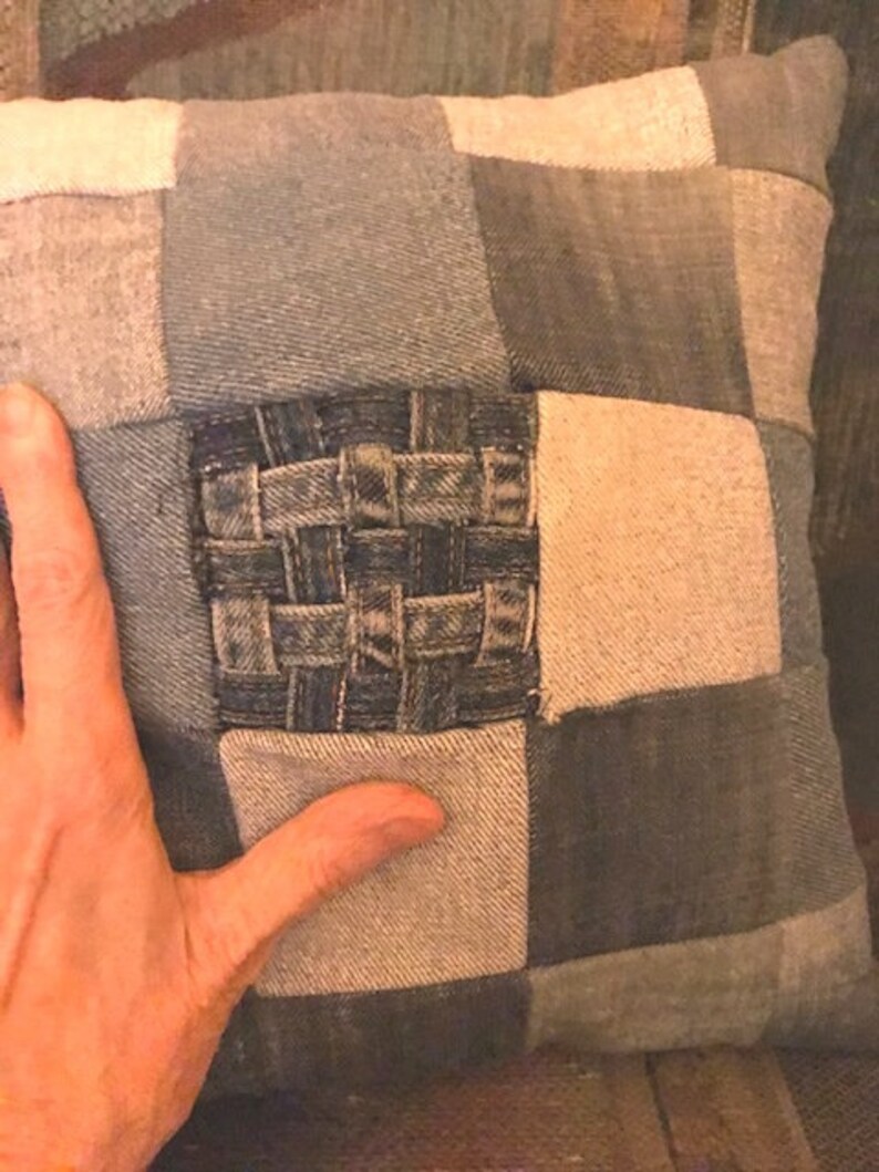 Pu&ograve; includere: Un cuscino quadrato realizzato in tessuto di jeans patchwork. Il cuscino ha un quadrato di jeans intrecciato al centro.