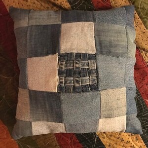 Pu&ograve; includere: Una federa patchwork realizzata in tessuto denim in diverse tonalit&agrave; di blu. La federa ha un quadrato di denim intrecciato al centro.