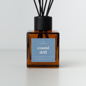 May include: A brown glass fragrance reed diffuser with a black cap and reeds. The label reads "Coastal Drift" with scent notes of sea salt, driftwood, and eucalyptus. Designed for home fragrance.