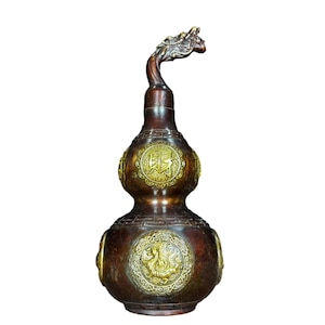 May include: A bronze-colored gourd-shaped decorative vase with gold accents. The vase features a dragon head at the top and circular gold medallions with Chinese characters and a dragon design. The vase is a decorative item.