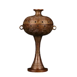 May include: A bronze-colored incense burner with a bulbous, perforated top and a slender, ornate stem. The top features small circular holes and is adorned with intricate patterns. Two small handles are on the sides. The base is round and also decorated.