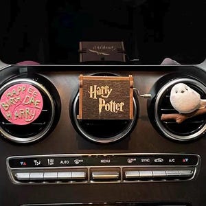 May include: A car air vent decoration set featuring a pink circular piece with the text "Happy Birthday Harry", a wooden box with "Harry Potter" text, and a white owl figurine perched on a branch.