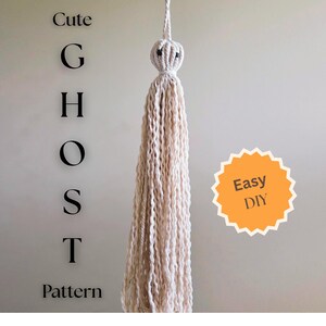 Könnte beinhalten: Handgefertigte, cremefarbene Makramee-Geisterdekoration mit schwarzen Perlenaugen und einem geknoteten Kopf. Der Text "Cute GHOST Pattern" wird vertikal links angezeigt, mit einem orangefarbenen "Easy DIY"-Aufkleber rechts. Ideal für Halloween.