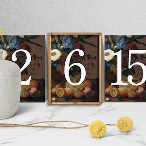 Puede incluir: Tres impresiones artísticas enmarcadas con pinturas de naturalezas muertas de flores y frutas. Los números 2, 6 y 15 están superpuestos en la obra de arte. Un jarrón blanco texturizado y acentos florales amarillos en primer plano.