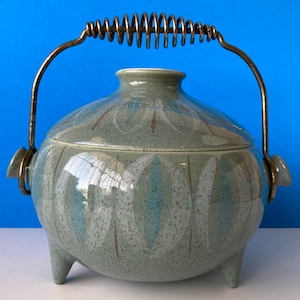 Könnte beinhalten: Eine Keramik-Auflaufform mit einem federbelasteten Griff. Die Form ist mit einem blauen und weißen Blatt-Muster verziert und hat drei Beine.