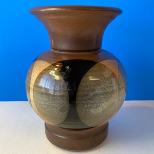 Op de afbeelding: Een keramische vaas met een bolvormig lichaam en een uitlopende bovenkant. De vaas heeft een colorblock-ontwerp met bruine, zwarte en beige secties. De basis is een donkerdere bruintint. De vaas is ongeveer 20 cm hoog.