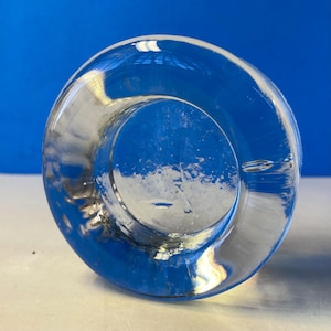 Puede incluir: Una taza de cerámica blanca con un asa negra y el texto "But First, Coffee" en negro, con una fuente de estilo manuscrito. La taza está sobre una superficie blanca.