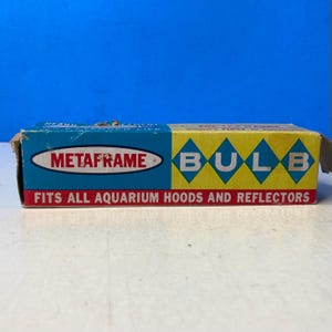 May include: A rectangular cardboard box for a Metaframe bulb. The left side is blue with the text Metaframe in a white oval. The right side is yellow with the word bulb in blue diamonds. The bottom red stripe reads fits all aquarium hoods.