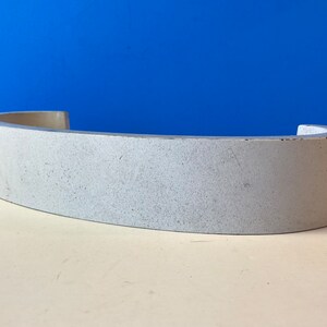 May include: A white, curved, ceramic piece with a rough, textured surface.
