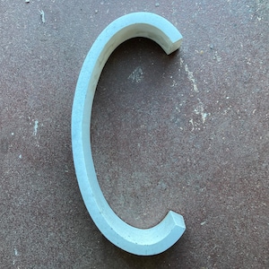 May include: A white, curved, ceramic piece shaped like the letter C.