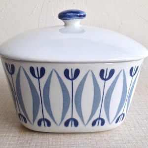 May include: White ceramic butter dish with a blue and grey geometric pattern. The lid has a blue knob.